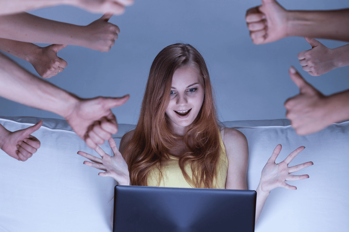 Woman sitting with a laptop surrounded by multiple hands showing thumbs up.